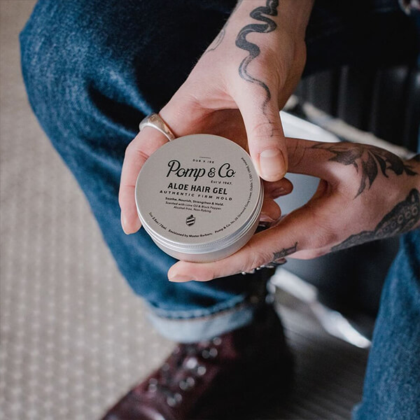 Ung mand i mørkeblå jeans holder hårgelé fra Pomp & Co. i hånden.